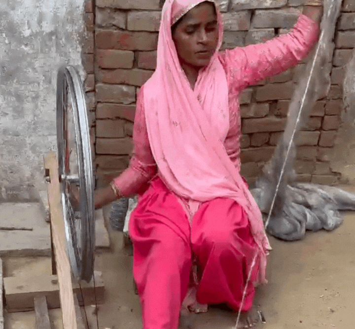 Woman spinning a wheel of wool to make a natural wool rug