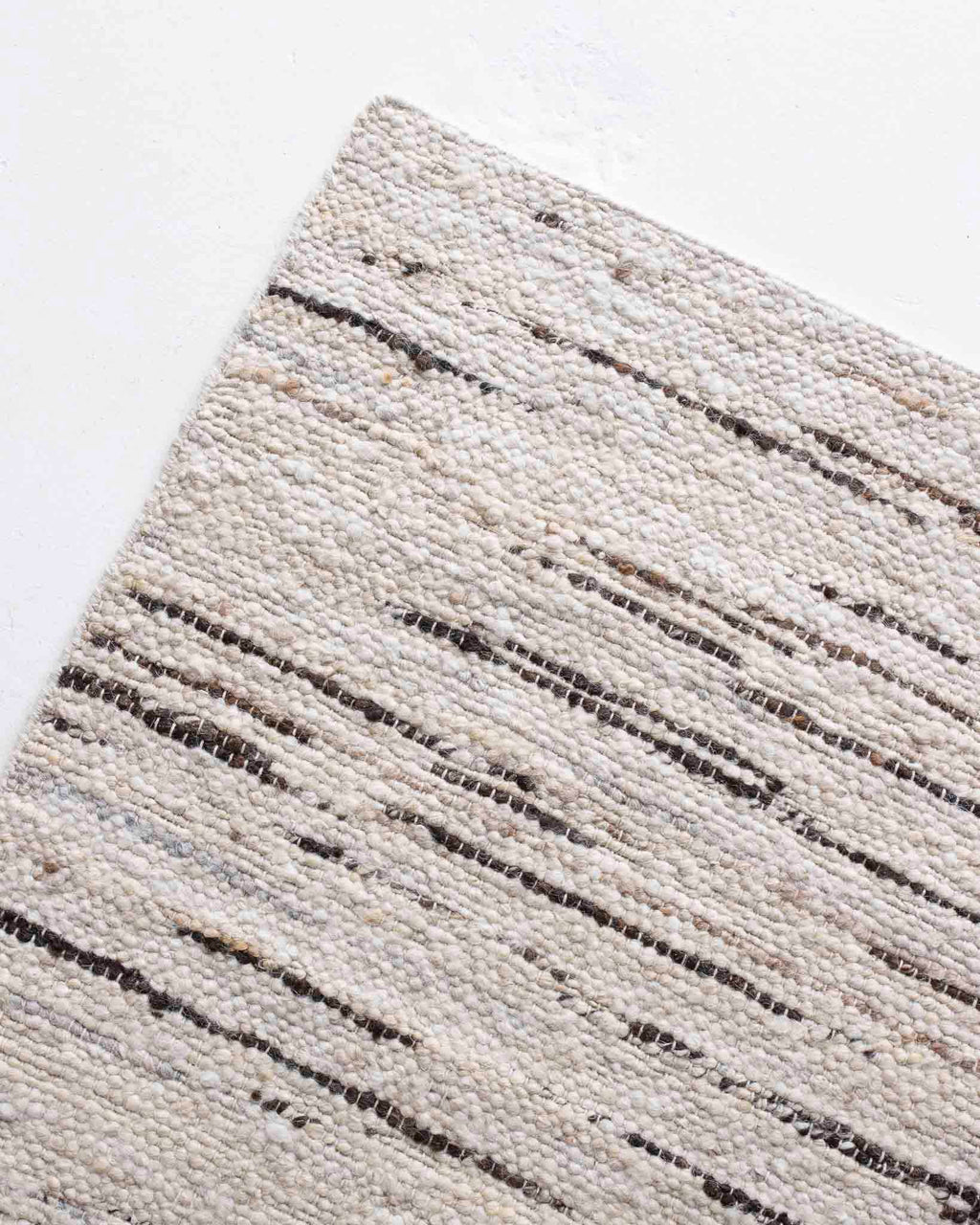 Close-up of a textured beige rug with dark brown  pattern from Rugs for Good.