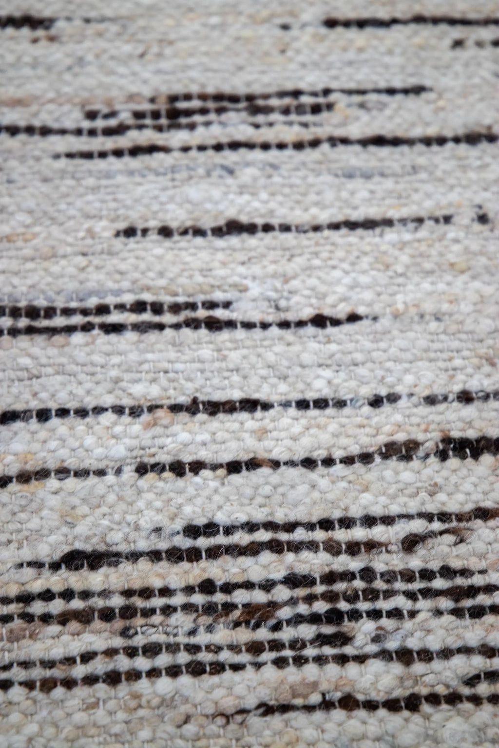 Close-up of a textured wool rug with chocolate and beige pattern from Rugs for Good.