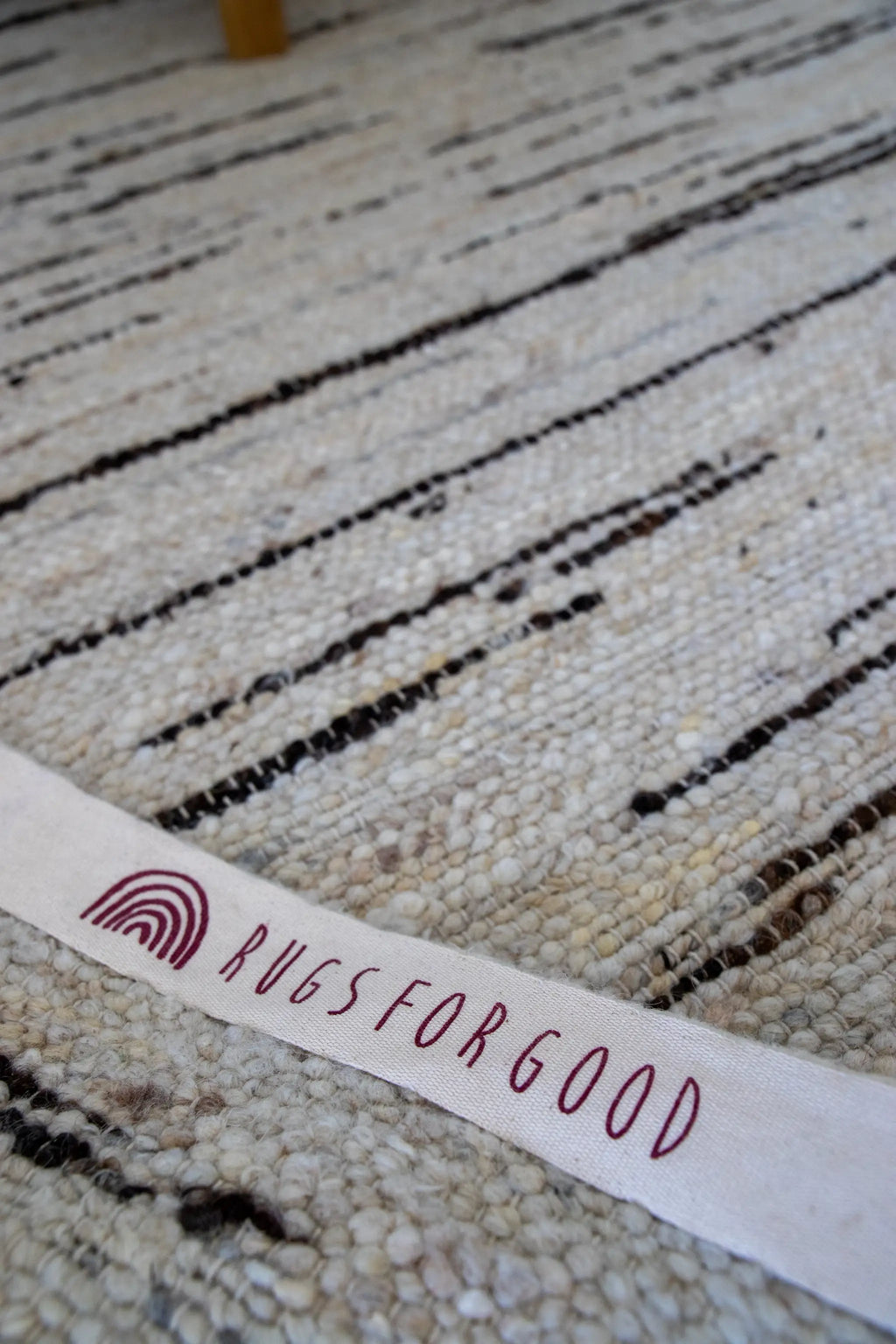 Beige wool rug with 'Rugs for Good' label